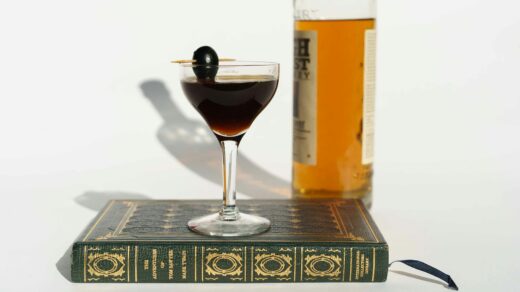 martini cocktail on book near bottle of whiskey