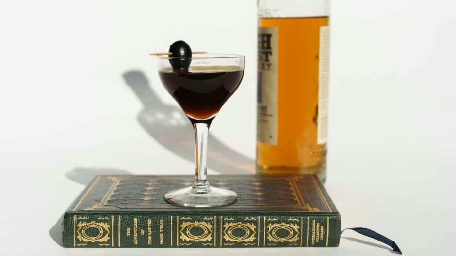 martini cocktail on book near bottle of whiskey