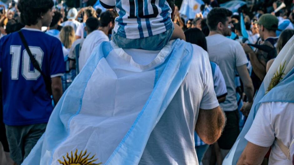 child piggybacking on fathers shoulders in march of argentina football fans