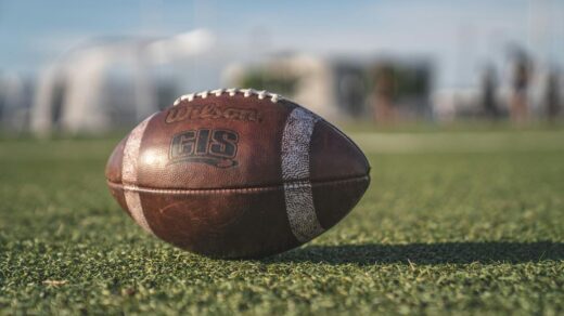 Close-up of a Wilson football on green grass in an outdoor sports setting, perfect for sports-themed visuals.
