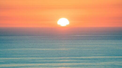 Sun setting over a calm ocean horizon