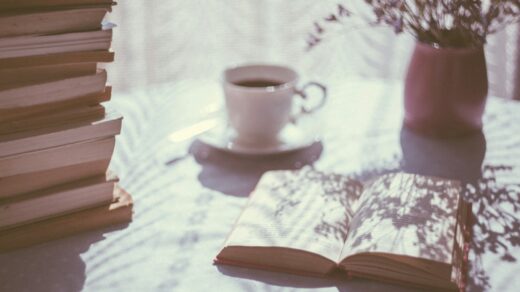 open book beside white ceramic teacup on saucer