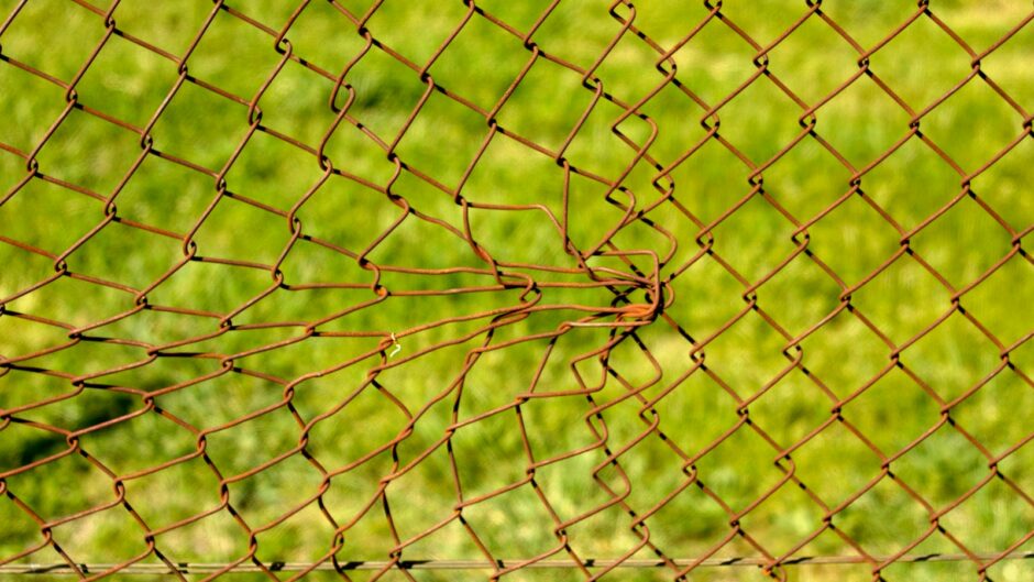 a close up of a fence with grass in the background